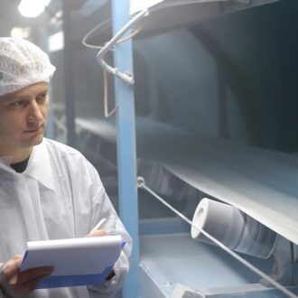 Safety professional inspecting industrial machinery for combustible dust accumulation or hazards